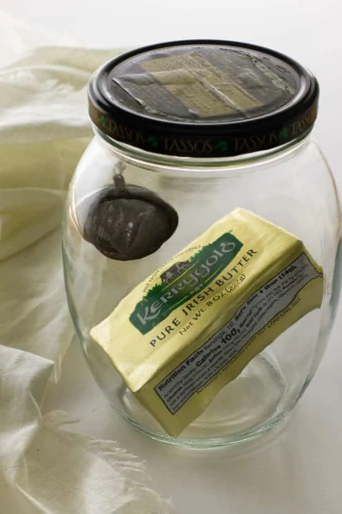 A block of butter in a jar with a black truffle for gas infusion.