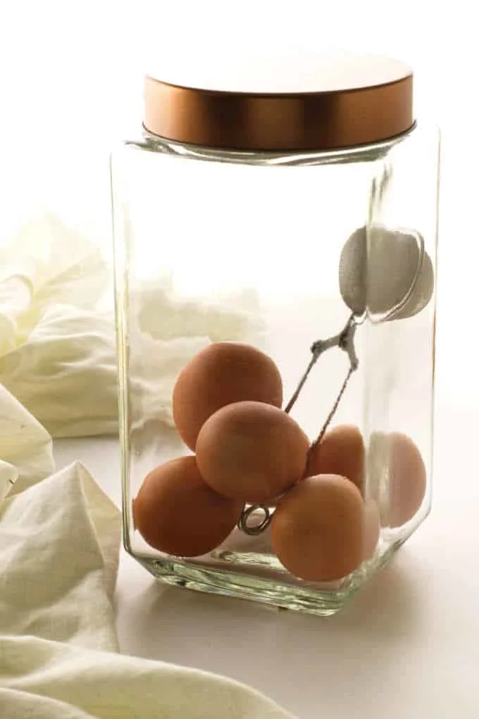5 eggs in a jar with a black truffle in a tea infuser to infuse the eggs with black truffle flavor.