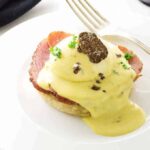 Eggs Benedict with White Truffled Hollandaise Sauce and a slice of a truffle.