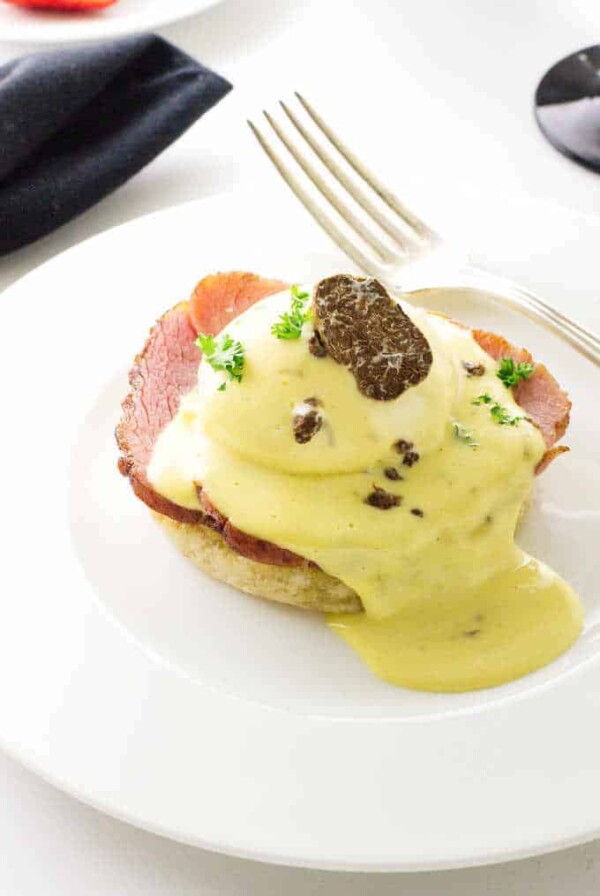 Eggs Benedict with White Truffled Hollandaise Sauce and a slice of a truffle.