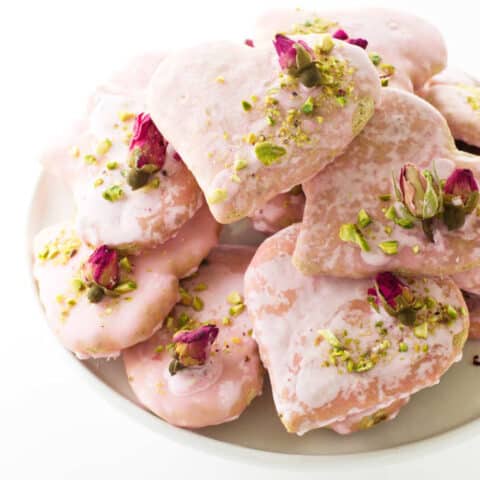 Plate of heart-shaped biscotti cookies with dried rose buds and chopped pistachios