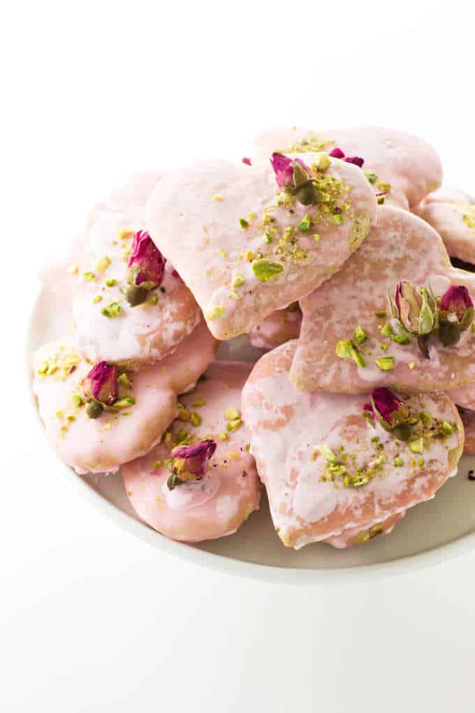 Plate of heart-shaped biscotti cookies with dried rose buds and chopped pistachios
