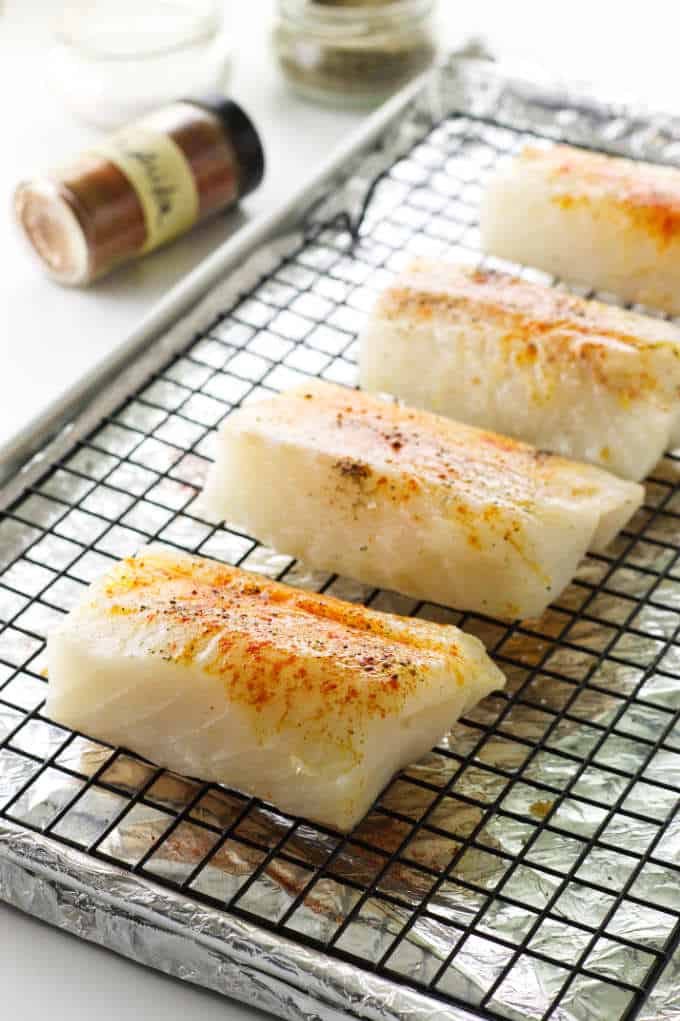 seasoning of salt, pepper and paprika on Pacific Cod, ready to broil