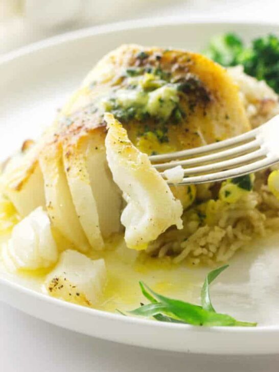 Broiled Pacific Cod with a bite on a fork, melted lemon tarragon butter