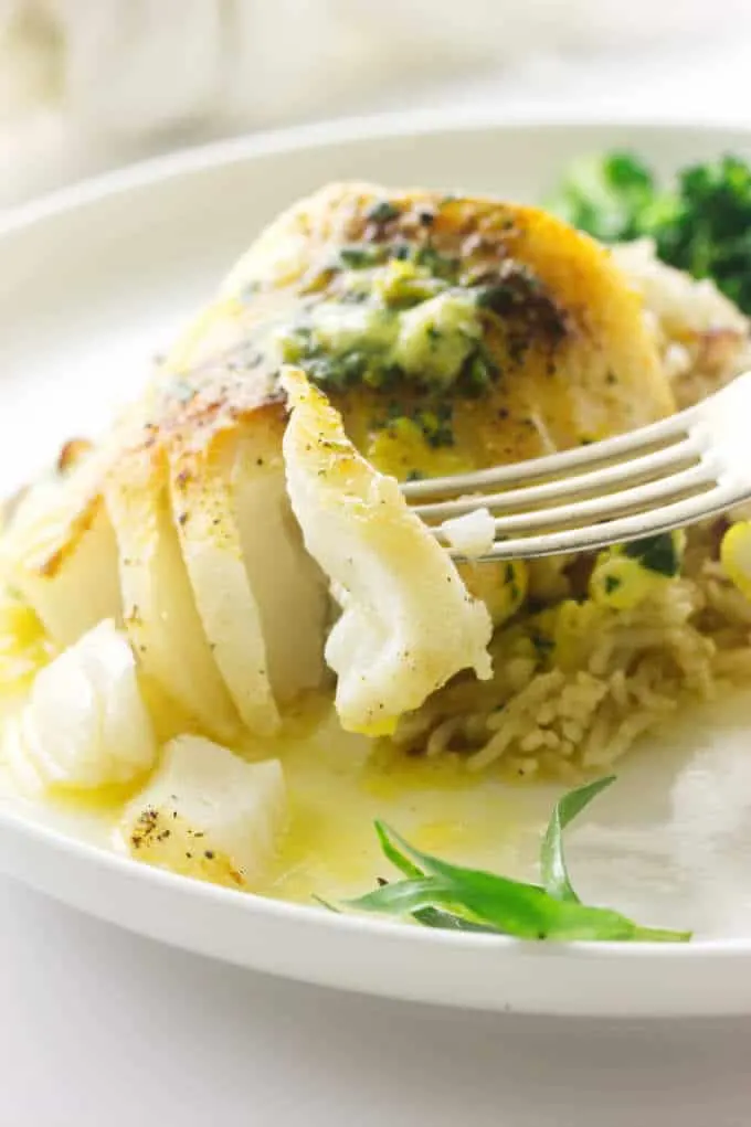 Broiled Pacific Cod with a bite on a fork, melted lemon tarragon butter