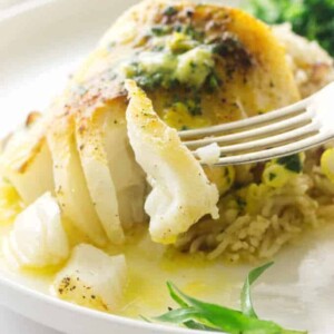 Broiled Pacific Cod with a bite on a fork, melted lemon tarragon butter