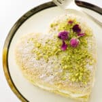 Mini layer cakes dusted with confectioners' sugar and garnished with pistachios and dried roses