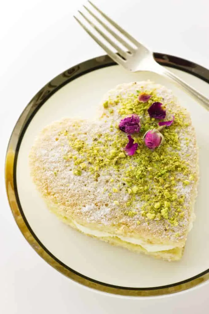 Heart cake dusted with confectioners' sugar and garnished with pistachios and dried roses