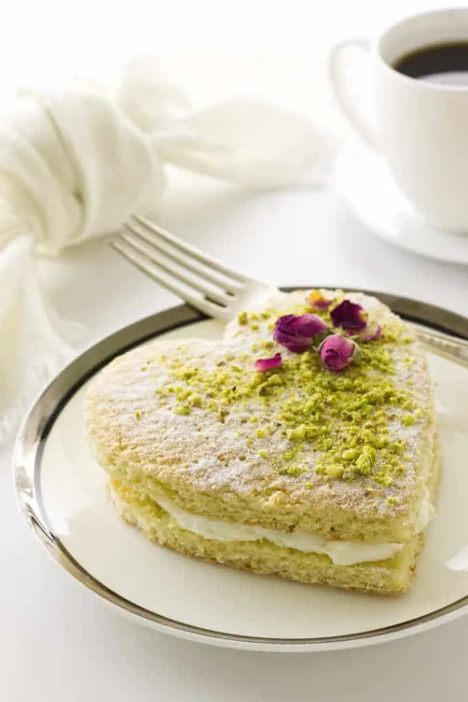 Heart cake dusted with confectioners' sugar and garnished with pistachios and dried roses