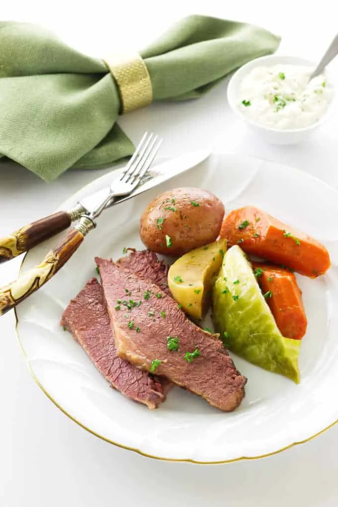 Serving of corned beef, cabbage, turnip and carrots. Dish of Fresh Horseradish Aioli Sauce in background
