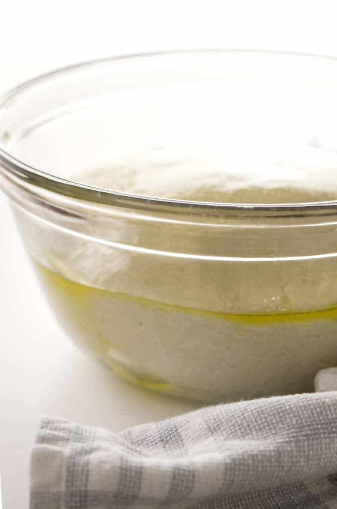 Sourdough pizza dough rising in a bowl.