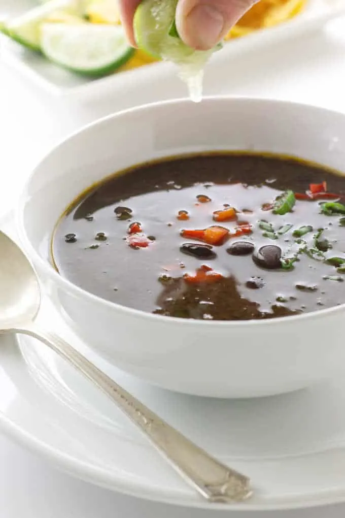 Bowl of chipotle black bean soup with lime juice squeezed on top