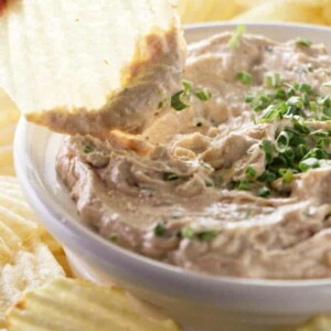 A chip being dipped into French onion dip.