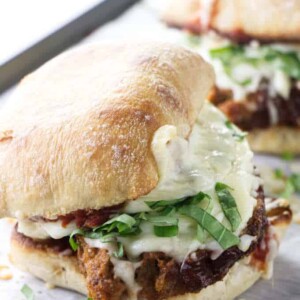 Closeup of a hot meatloaf sandwich with melted cheese and fresh basil.