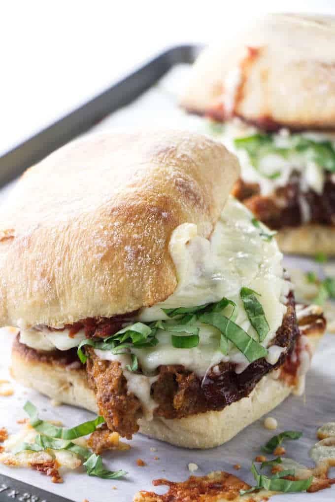 Closeup of a hot meatloaf sandwich with melted cheese and fresh basil.