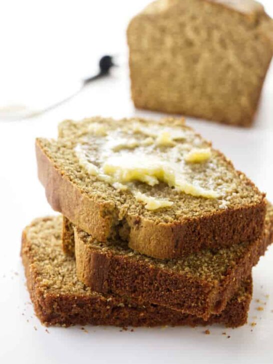 Slices of barley bread with butter and a loaf of bread in the background.