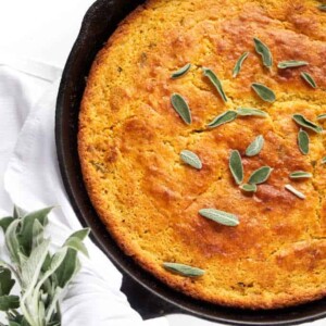 Brown butter skillet cornbread with sage leaves on top.