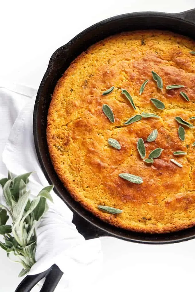 Brown butter skillet cornbread with sage leaves on top.