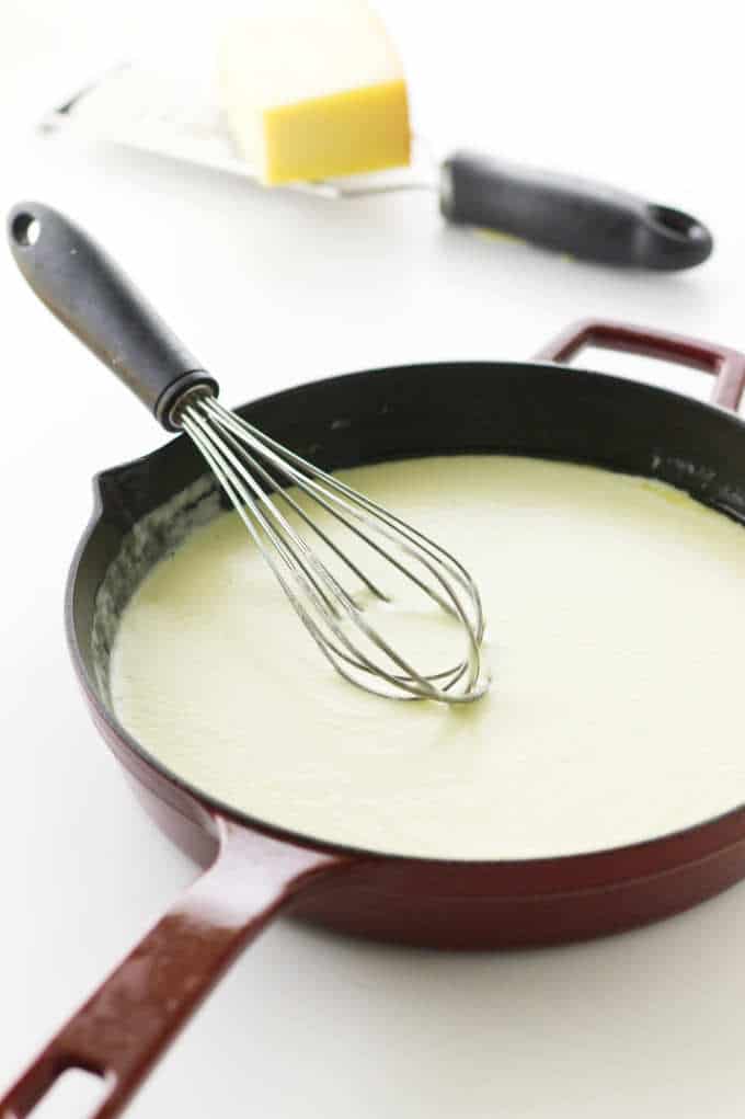 Creamy, garlic-y sauce for pasta, whisk and cheese/microplane in background