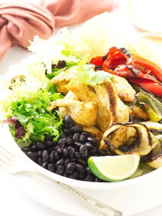 Bowl of black beans, roasted chicken, onions, red/green bell pepper and lime wedge
