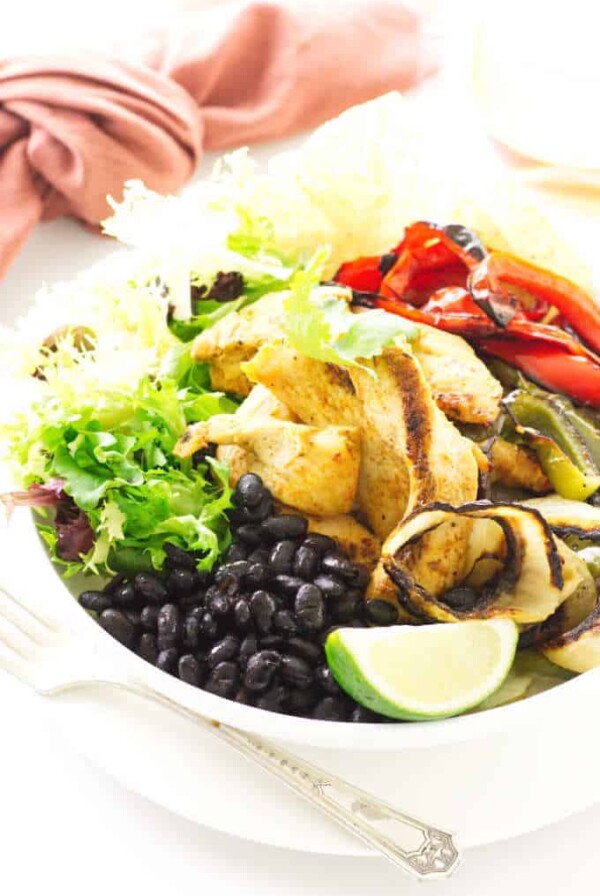 Bowl of black beans, roasted chicken, onions, red/green bell pepper and lime wedge