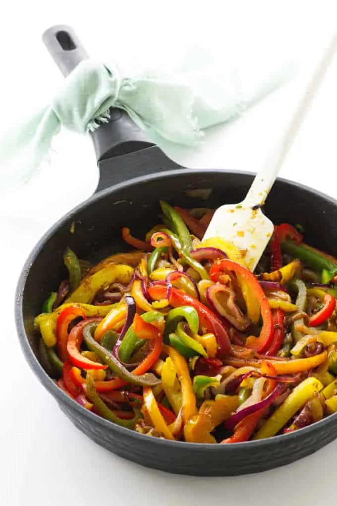 Skillet with fajita vegetables and a spatula