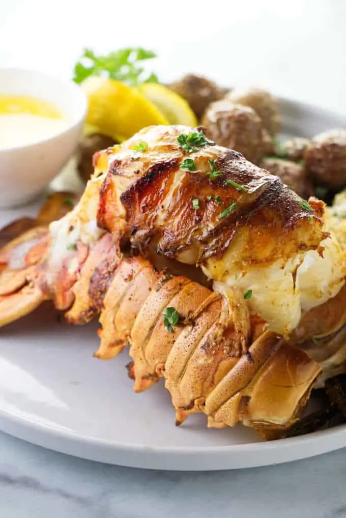 Broiled lobster tail on a serving plate.