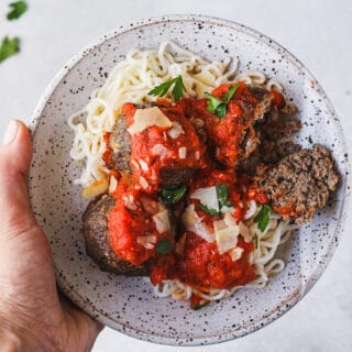 holding a plate of low-carb spaghetti and keto Italian meatballs