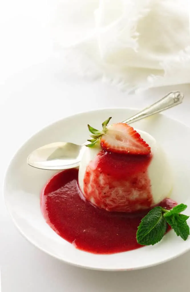 Overhead view of a serving of panna cotta in a puddle of strawberry sauce