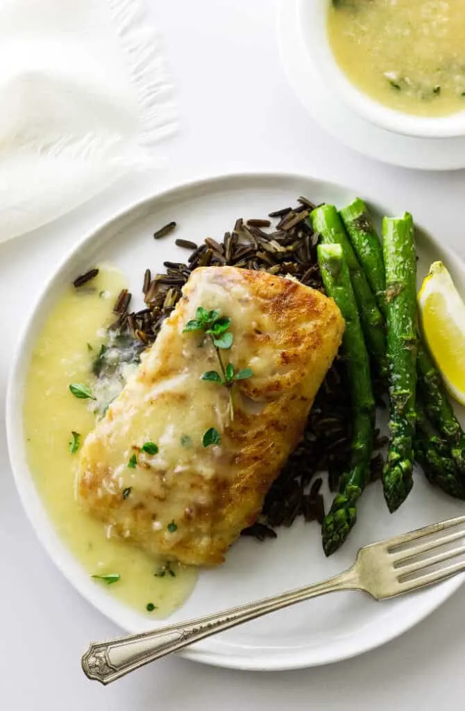 Overhead view of plated cod fillet with lemon-garlic sauce, wild rice and asparagus