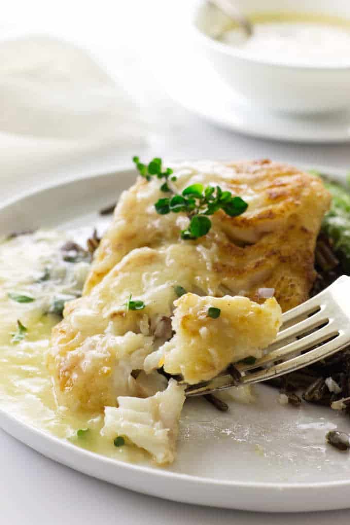 close up view a bite on a fork of pan roasted cod with lemon-garlic sauce