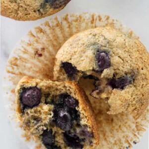 Muffin broke in half showing blueberries inside.