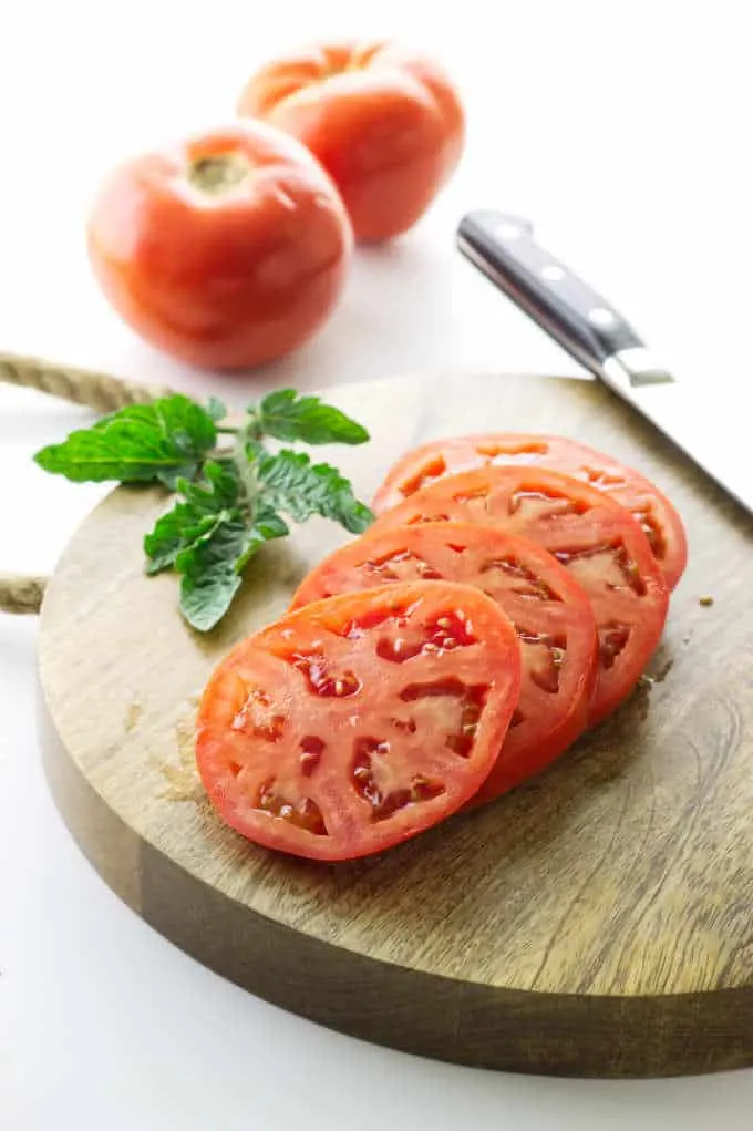 Slices of fresh tomato on a cutting board.