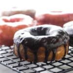 A chocolate covered sourdough donut on a cooling rack.