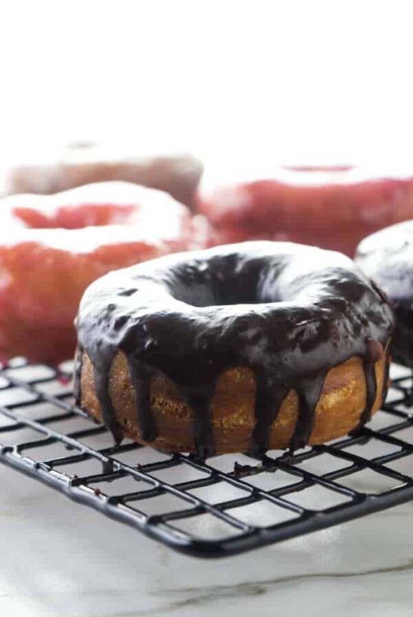 A chocolate covered sourdough donut on a cooling rack.