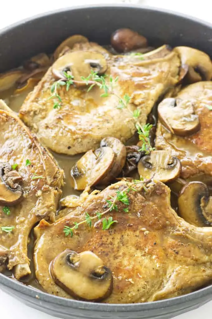 Close up of pork chops and mushrooms in a skillet