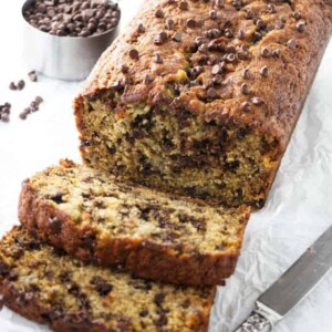 Slices of chocolate chip banana bread next to a loaf of banana bread.