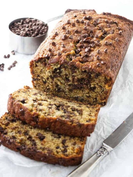 Slices of chocolate chip banana bread next to a loaf of banana bread.