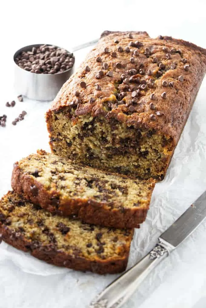 Slices of chocolate chip banana bread next to a loaf of banana bread.