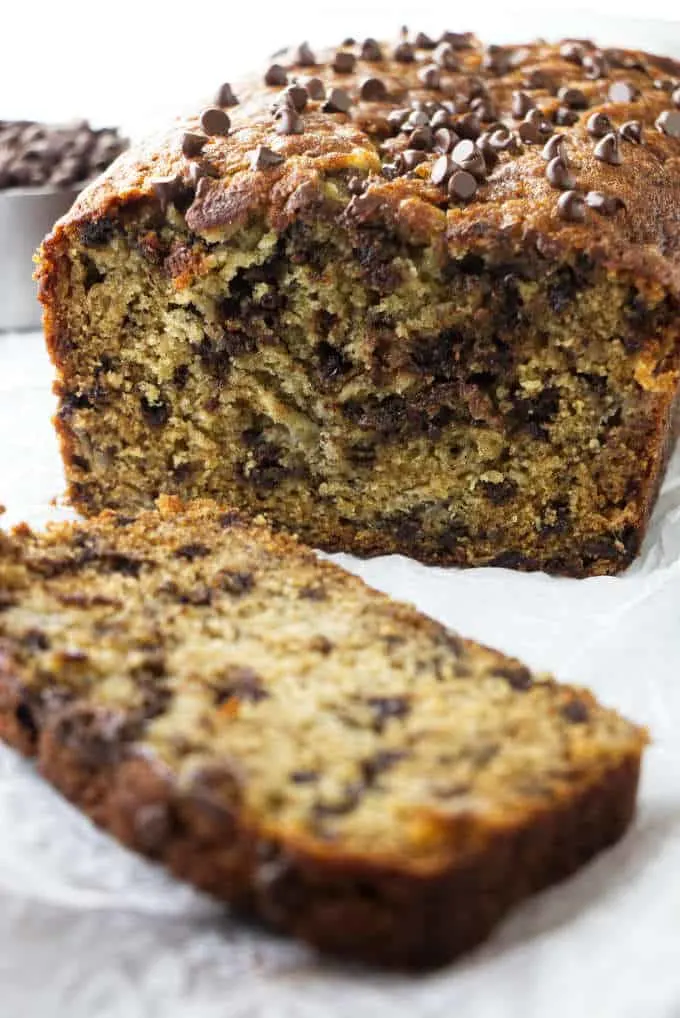 A loaf of chocolate chip banana bread with a slice on the side.