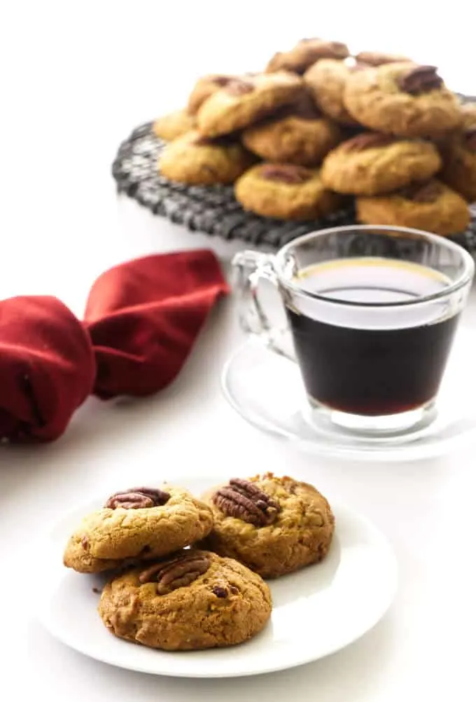 Three cookies on a plate, coffee, cup/saucer, red napkin and stack of cookies