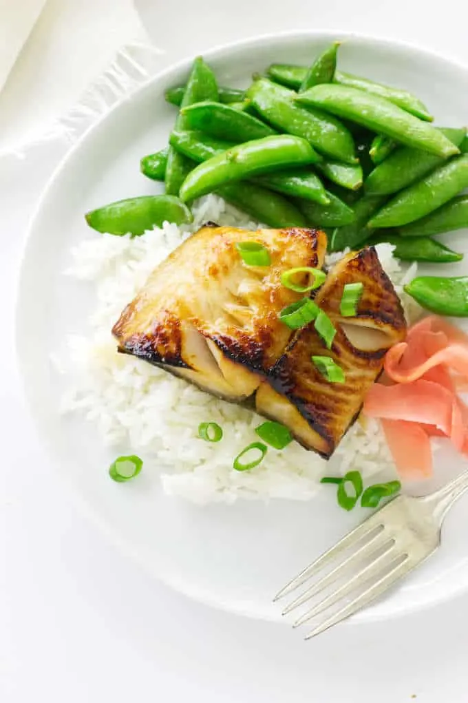 Overhead view of a serving of miso teriyaki sablefish, rice, pickled ginger and snap peas