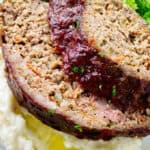 Two slices of pork and beef meatloaf on a pile of mashed potatoes.