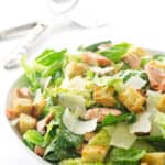 Large bowl filled with salad, serving utensils in background