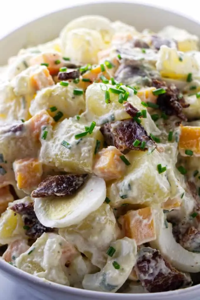 A serving bowl of potato salad with bacon and eggs.