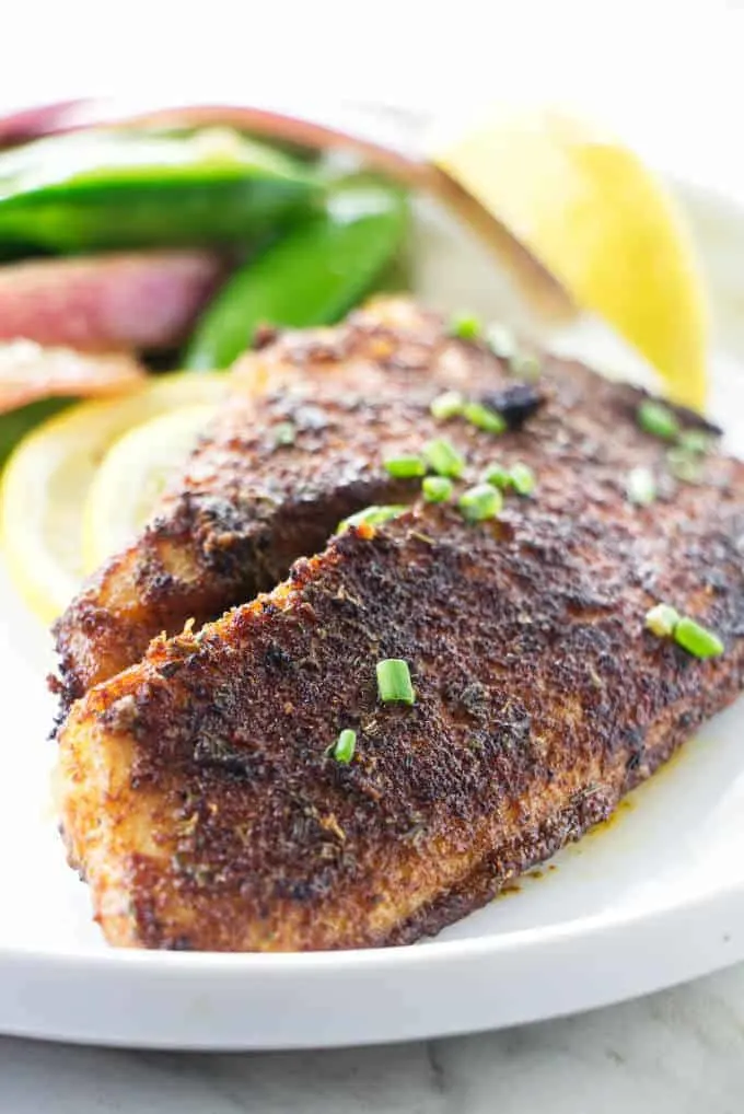 A fillet of blackened tilapia on a plate.