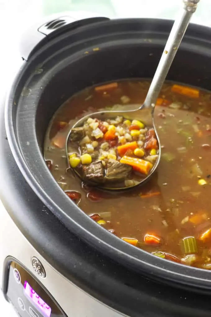 Soup in a slow cooker with a ladle of soup