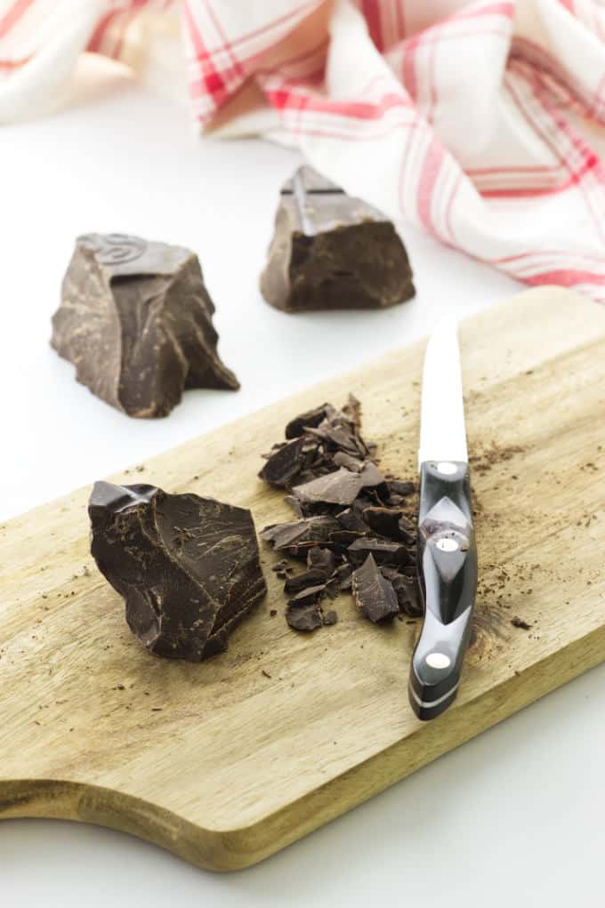 Cutting board with chopped chocolate, chocolate chunks and napkin in background