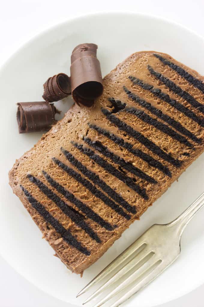 Overhead view of a slice of double chocolate Icebox cake and chocolate curls on a serving plate.