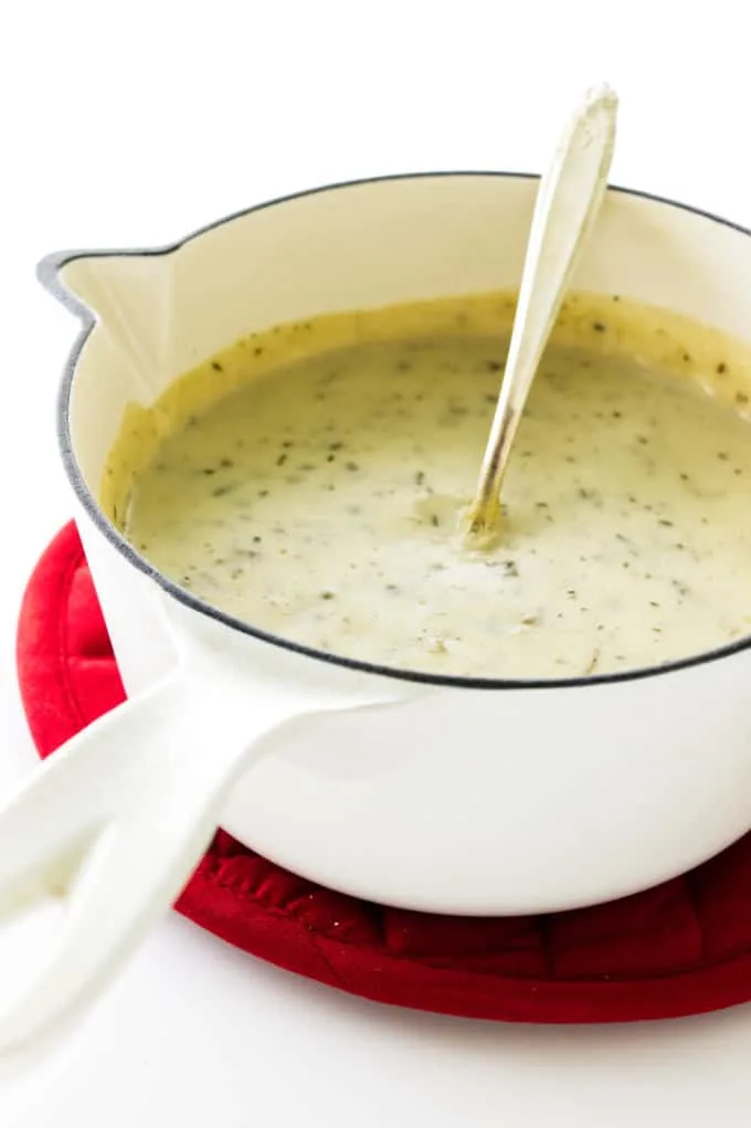 Saucepan with homemade condensed cream of mushroom soup, sitting on a red mat.